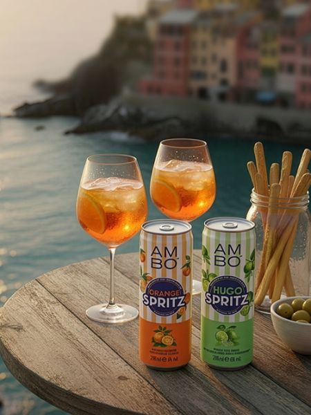 AMBO Orange Spritz and Hugo Spritz cans with two spritz cocktails on a seaside table.